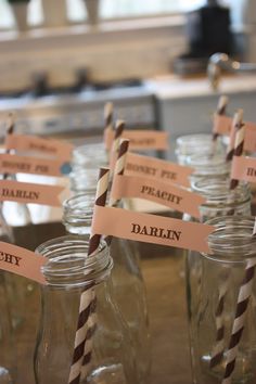 there are many mason jars with paper straws in them and name tags on the top