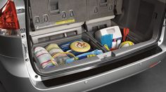 the back end of a silver car with its trunk open and various items in it