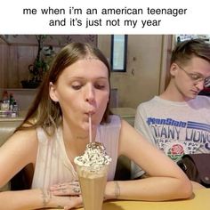 two people sitting at a table drinking milkshakes