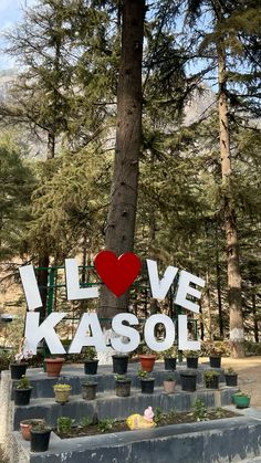 a sign that says i love kassol in front of some potted plants