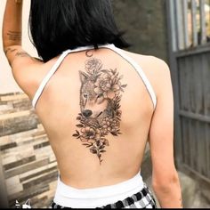 the back of a woman's body with flowers and a wolf tattoo on it