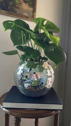 a mirror ball planter sitting on top of a table next to a book and window