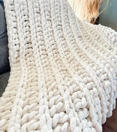 a white knitted blanket sitting on top of a couch