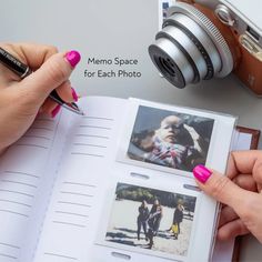 a person holding a pen and taking pictures with an open book next to a camera