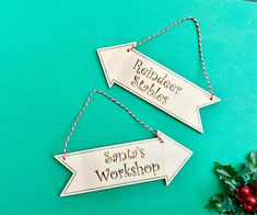 two wooden signs hanging on a green wall next to a holly wreath and red berries