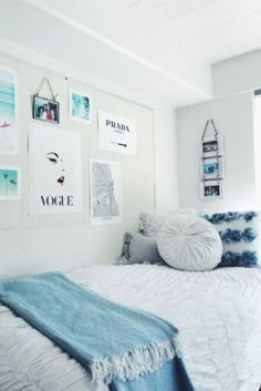 a bedroom with white walls and pictures on the wall above the bed, along with blue throw pillows