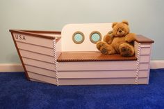 a teddy bear sitting on top of a toy boat in a room with blue carpet