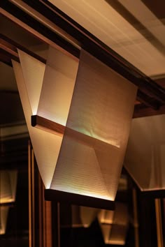 a light fixture hanging from the ceiling in a room with wood paneling and lighting