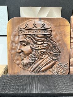 a carved wooden plaque with a man's face and crown on it, in front of a black background