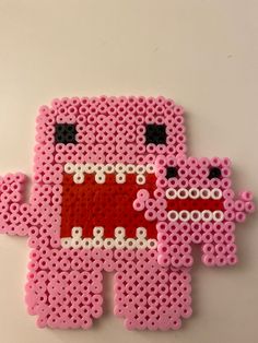 an image of a pink pixelo beaded object on a white surface with black dots