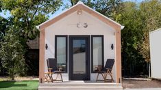 a tiny house with two chairs on the front porch