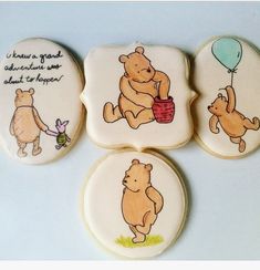 four decorated cookies with winnie the pooh images on them, one is holding a balloon