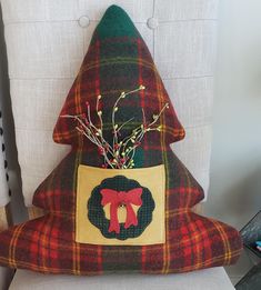 a plaid christmas tree pillow sitting on top of a white chair