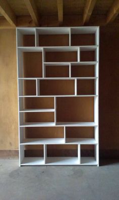 a white book shelf sitting on top of a cement floor next to a wooden ceiling