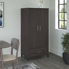 a brown cabinet sitting next to a table and chair in a room with white walls