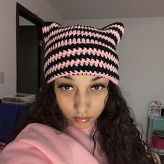 a woman wearing a pink and black knitted hat with cat ears on her head