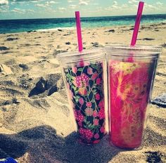 two cups sitting on top of a sandy beach