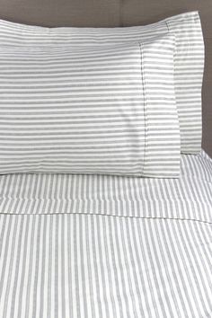 a bed with white and grey striped sheets