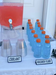 a table topped with blue water bottles and orange caps next to a sign that says coolant