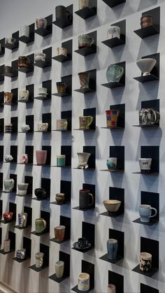 the wall is filled with many cups and saucers on shelves that are stacked together