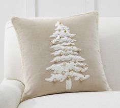 a white christmas tree pillow sitting on top of a couch