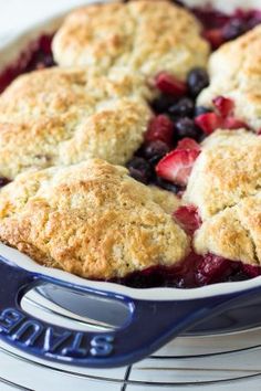 a close up of a pie in a pan with berries on it and a blue spatula