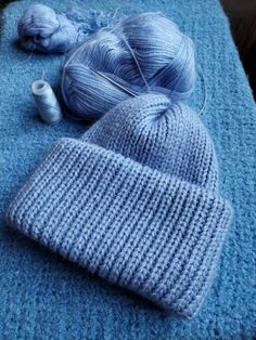 two balls of yarn are sitting on a blue blanket next to a ball of thread