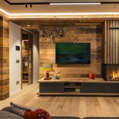 a living room filled with furniture and a flat screen tv on top of a wooden wall