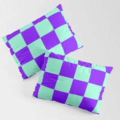 two purple and green checkered pillows sitting on top of a white table next to each other