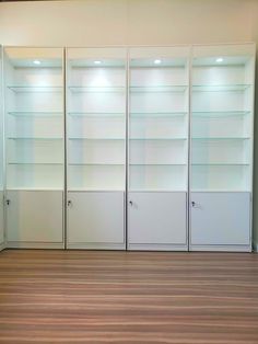 empty white bookcases in an empty room with hard wood flooring and wooden floors