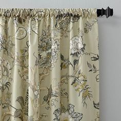 a curtain with floral print hanging on a wall next to a black rod - end