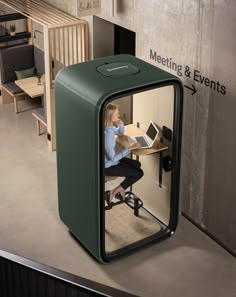 a woman sitting at a desk in an office cubicle with a laptop on it