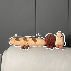 two stuffed animals are sitting on the back of a couch, one is brown and white