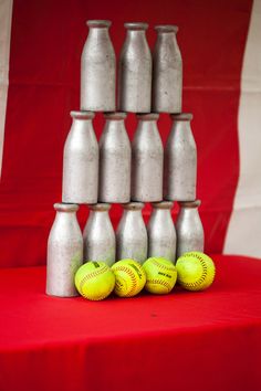 several silver vases are stacked on top of each other with softballs in front of them