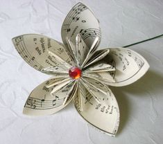 an origami flower with musical notes and a red bead in the center