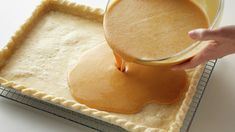 a person pouring batter into a pie crust