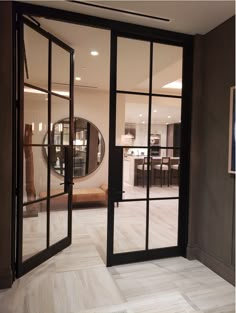 an open door leading to a living room and dining area with large mirrors on the wall