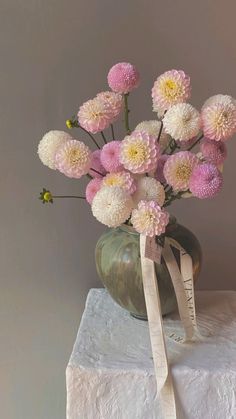 a vase filled with lots of pink and white flowers sitting on top of a table