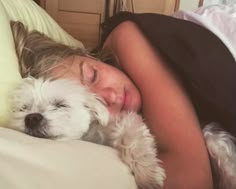 a woman sleeping in bed with her dog