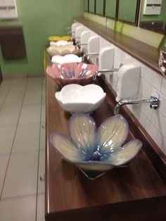 a row of bathroom sinks sitting on top of a wooden counter