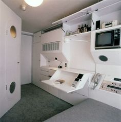 a room with white walls and shelves filled with electronic equipment, including a microwave on the wall