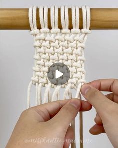 two hands are working on an object that looks like a macrame weaving project