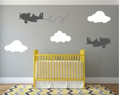 a baby's room with an airplane and clouds wall decal on the wall