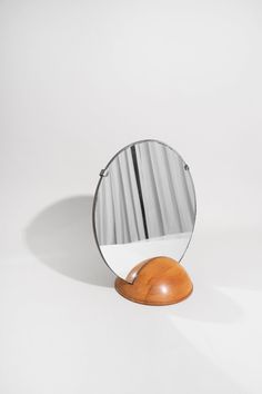 a round mirror sitting on top of a wooden table next to a white wall and floor