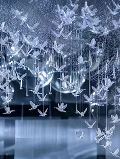 the glass is hanging from the ceiling and has many small white birds on it's wings