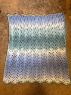 a blue and white crocheted blanket laying on the floor