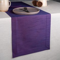 a purple table runner with a fork and knife resting on the place setting for an elegant dinner