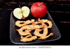 apple slices and an apple on a black plate with the peels cut out to look like letters