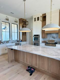 a kitchen with an island and two pendant lights hanging from the ceiling over the stove