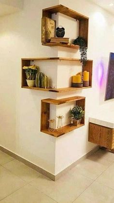 three wooden shelves on the wall with plants and vases in them, one shelf is made out of wood